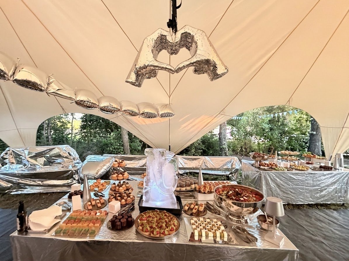 Festival tent interior with a mirror-tiled hand-heart sculpture above a silver banquet table