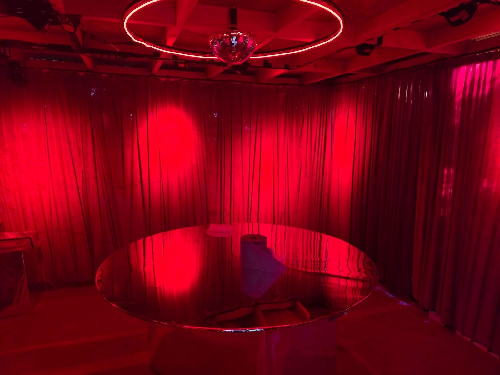 Red velvet speakeasy interior lit by a neon ring and mirror ball